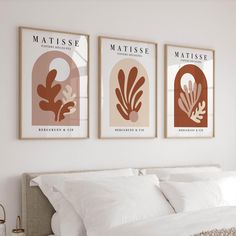 three framed art prints on the wall above a bed