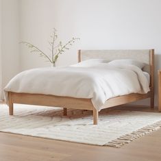 a white bed sitting on top of a hard wood floor next to a wooden dresser