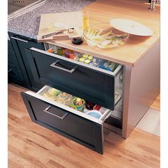 an open drawer in the middle of a kitchen counter with food and drinks on it