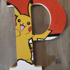 a wooden letter with a pikachu painted on the front and bottom, sitting on top of a wood floor