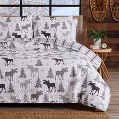 a bed covered in a white and black moose print comforter with pillows on it