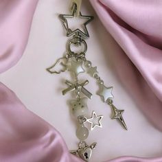 a close up of a key chain with charms on it's side and a pink satin background