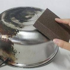 a person is using a sponge to clean the bottom of a metal pan with a sponge