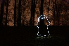 a person standing in the woods at night with their head turned to look like a ghost