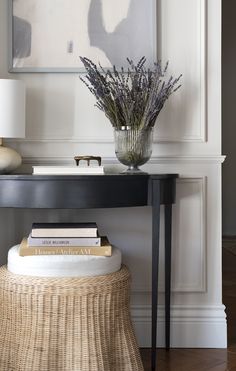 a table with a vase and some books on it next to a lamp in a room