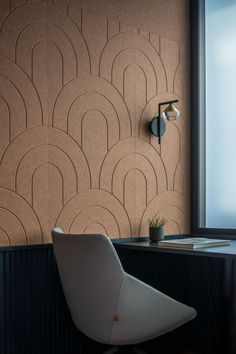 a white chair sitting in front of a window next to a wall mounted light on the side of a wooden table