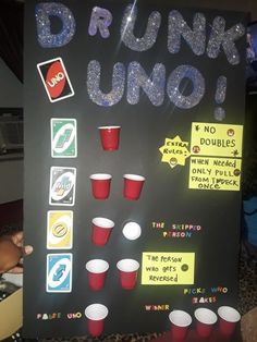 a sign that says drunk uno with cups and sodas on it in front of a table