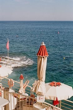 an outdoor dining area overlooking the ocean with umbrellas and chairs