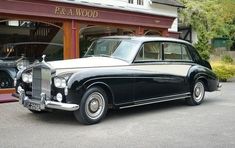 an old black and white car parked in front of a building