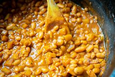 the beans are being stirred in the pot with a wooden spoon to stir them together