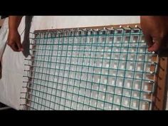 two men are working on a wall made out of glass jars and wire mesh netting