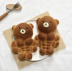 two teddy bears made out of waffles sitting on a plate next to a fork and knife