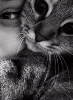 a woman is holding her cat close to her face