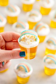 a person holding a cupcake in their hand with frosting and sprinkles on it