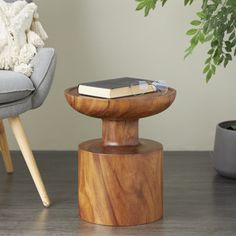 a wooden table with a book on it next to a chair and potted plant