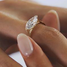 a woman's hand with a diamond ring on her finger and the other hand holding it