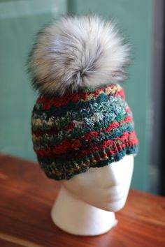 a knitted hat with a pom - pom sits on a mannequin head