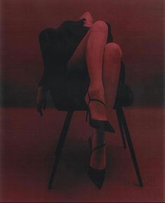 a woman sitting in a chair with her legs crossed and wearing high heeled shoes