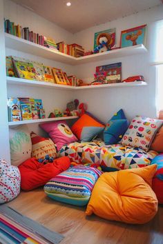 a room filled with lots of colorful pillows and bookshelves on the shelves above