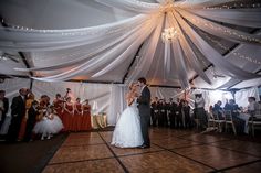 a bride and groom dance on the dance floor in front of their wedding party guests