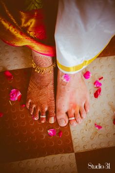 the feet of a bride and groom with rose petals scattered around them on a tiled floor