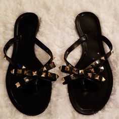 Black Thong Bow Sandals With Gold Spikes On The Bow And Sides. One Spike Is Missing On The Right Sandal. New In Package Without Tag. Adjustable Black Jelly Sandals For Summer, Black Jelly Sandals For Summer, Black Jelly Sandals For Summer Vacation, Black Toe Post Flip Flops For Beach Season, Black Jelly Sandals For Beach Season Vacation, Black Jelly Sandals For Beach Vacation, Black Adjustable Summer Sandals, Black Flat Flip Flops For The Beach, Black Flip Flops For Beach