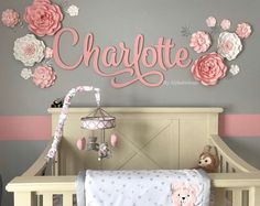 a baby crib with pink and gray flowers on the wall next to a teddy bear