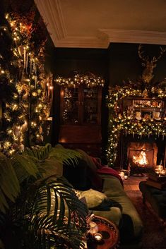 a living room decorated for christmas with lights and greenery on the walls, couches and fireplace