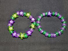 two purple and green bracelets sitting next to each other on a gray surface,