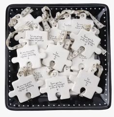 white puzzle pieces with words on them are in a black tray that is filled with silver chains