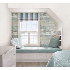 a bed sitting under a window next to a white dresser in a room with wooden floors