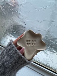 a person is holding a ceramic dish in front of a frosted window