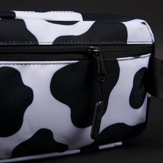 a black and white cow print toiletry bag on a black background with zippers