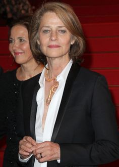 two women standing next to each other in front of red carpeted steps and stairs