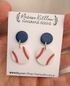 a pair of handmade earrings featuring a baseball ball and navy blue disc with red stitching