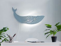 a blue whale lamp sitting on top of a white table next to potted plants