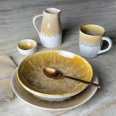 a table topped with plates and cups filled with liquid next to a pitcher on top of a counter