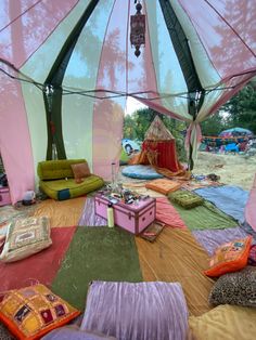 the inside of a tent with many different colored pillows and blankets on it's floor