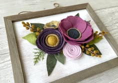 an embroidered flower is displayed in a wooden frame