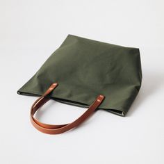 The Green Canvas tote is a canvas and leather tote handmade in the KMM & Co. studio in Atlanta. Each one is meticulously crafted from heavyweight canvas and gorgeous full-grain leather. Green Canvas is a type of cotton canvas known as duck cloth. It's one of the most durable types of cloth, and it's structured enough to stand up on its own. The Green Canvas tote comes standard with Tan handles. Everyday Canvas Bag With Duck Canvas Lining, Modern Canvas Bag With Canvas Lining For Everyday Use, Everyday Duck Canvas Bag With Double Handle, Duck Canvas Double Handle Bag For Everyday Use, Everyday Use Double Handle Duck Canvas Bag, Duck Canvas Tote Shoulder Bag With Leather Handles, Tote Shoulder Bag With Leather Handles In Duck Canvas, Duck Canvas Shoulder Bag For Daily Use, Modern Everyday Canvas Bag With Canvas Lining