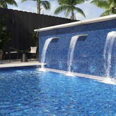 an outdoor swimming pool with blue tiles and water features waterfall casing down the side