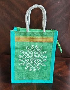 a small green bag sitting on top of a wooden table next to a white string