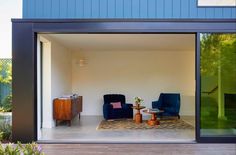 two blue chairs sitting on top of a wooden floor in front of a glass wall