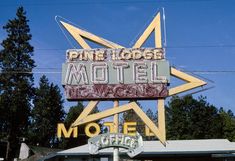 the pine lodge motel sign is painted yellow and has a star on it's roof