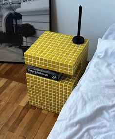 a yellow box sitting on top of a wooden floor next to a white bed and poster