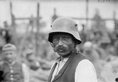 an old black and white photo of a man wearing a helmet with other men in the background