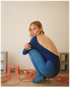 a woman sitting on the ground with her legs crossed and arms folded over her body