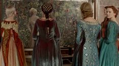 three women in dresses looking at an art work