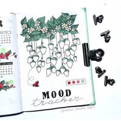 an open notebook with flowers and butterflies on the pages that read mood trackerr,