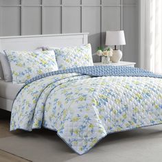 a white bed with blue and yellow flowers on it